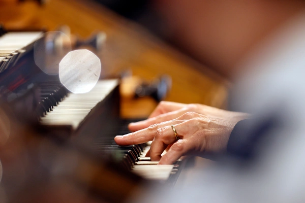 A person skillfully playing the organ inside a beautifully lit church, surrounded by ornate architecture. A person skillfully playing the organ inside a beautifully lit church, surrounded by ornate architecture.