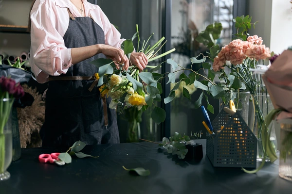 A woman carefully arranges a vibrant bouquet of flowers, showcasing her skill and creativity in floral design. A woman carefully arranges a vibrant bouquet of flowers, showcasing her skill and creativity in floral design.
