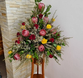 A beautifully arranged bouquet of flowers atop a wooden stand, highlighting a variety of blooms in an elegant presentation.