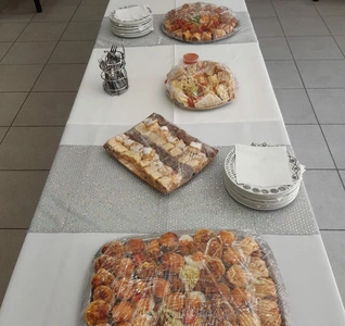 A lengthy table set with numerous plates, each brimming with a diverse selection of delicious food items.