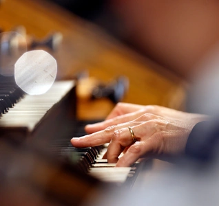 A musician performing on the organ in a church, with intricate details of the building visible in the background.
